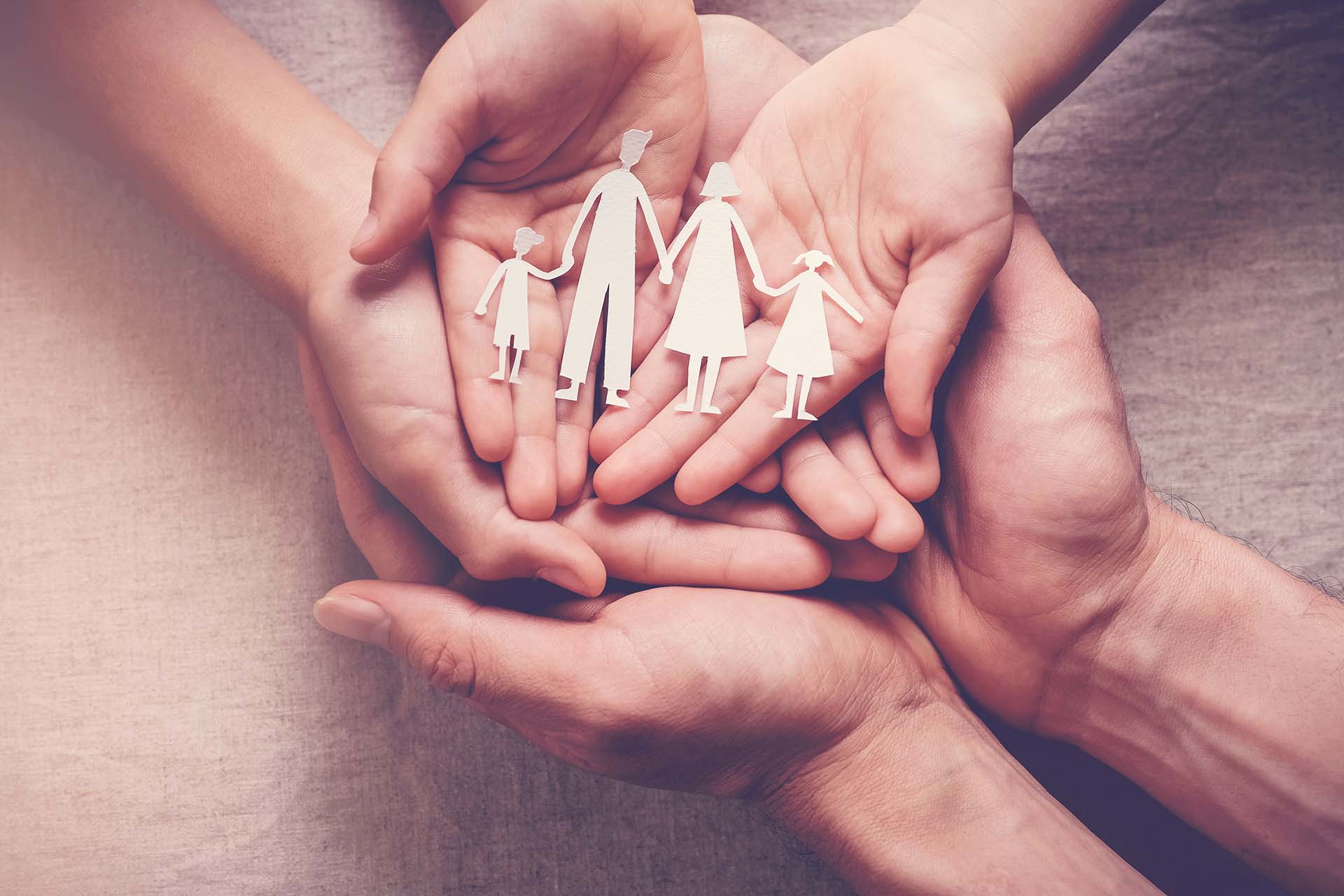 Hände einer Familie mit Scherenschnitt einer Familie auf den Handflächen